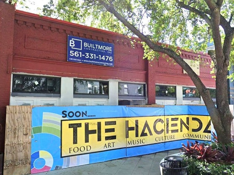 522 Clematis Street before opening: a brick storefront behind a hoarding reading Soon, The Hacienda — food, art, music, culture, community