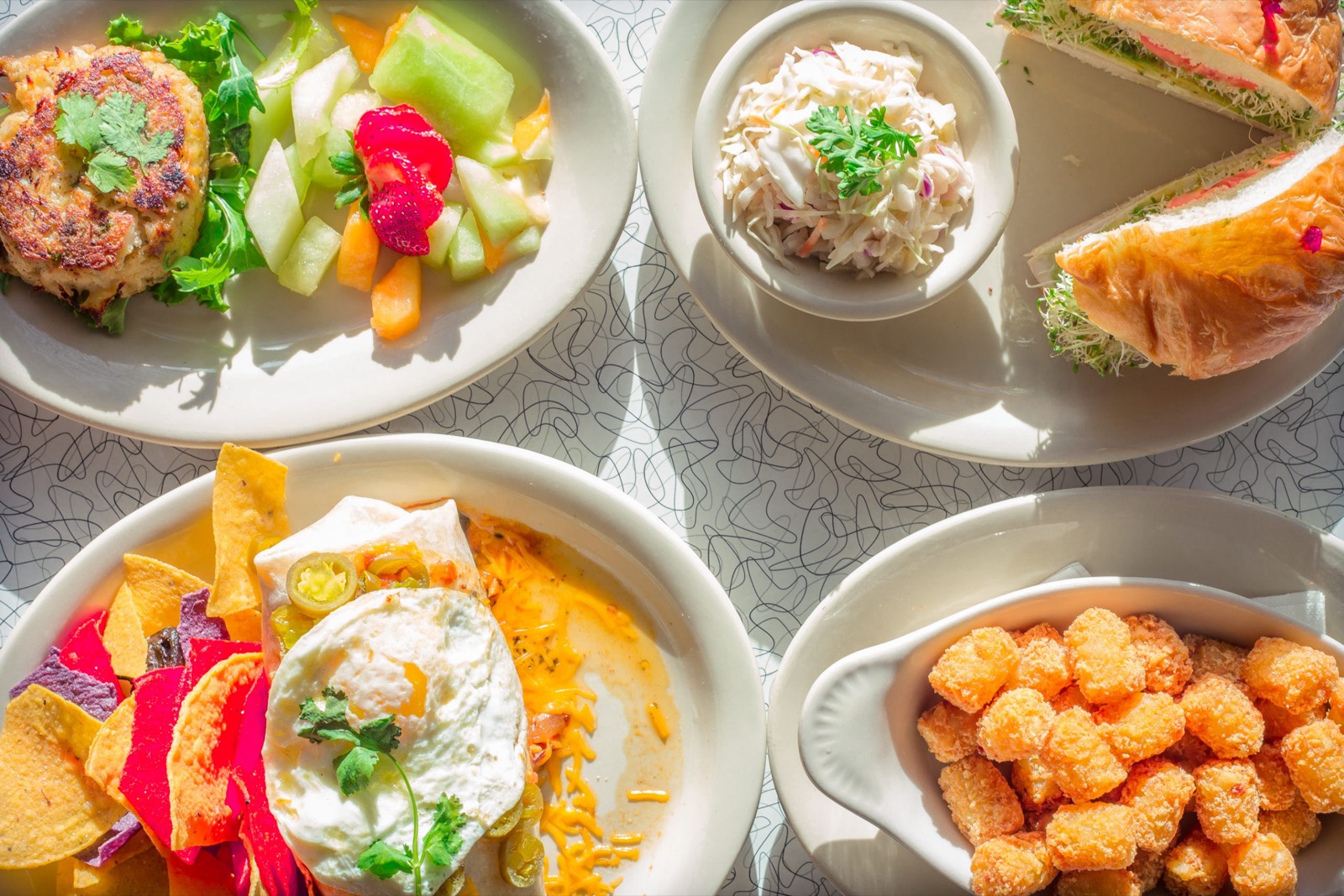 Plates at Howley's: crab cake, coleslaw, croissant sandwich, breakfast burrito and tater tots