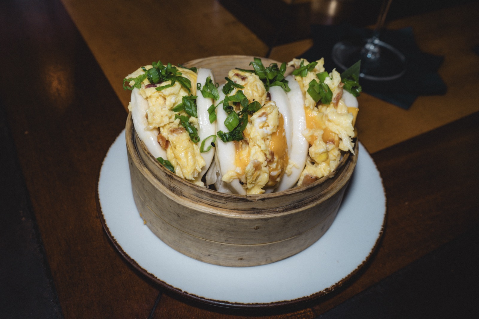 Steamed bao buns filled with scrambled egg, cheese and scallions in a bamboo steamer at Shanghai'd