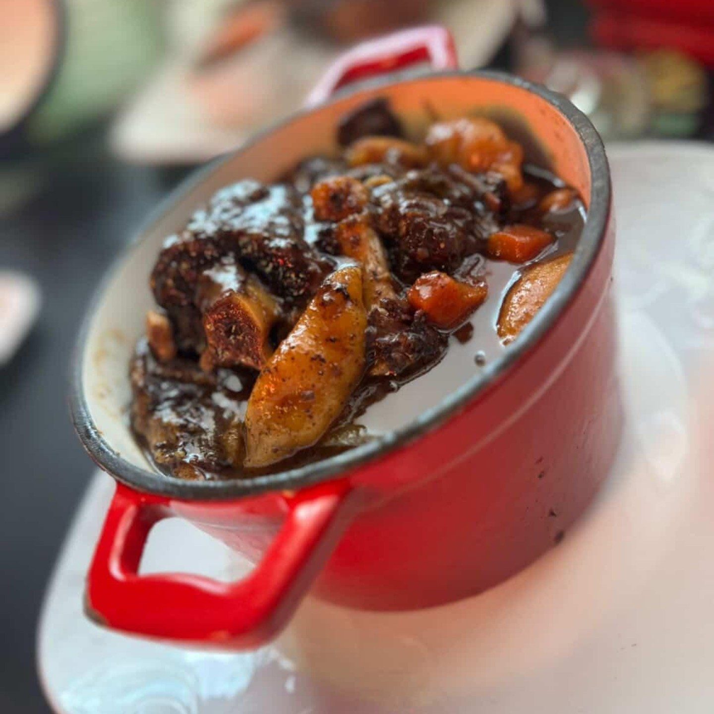 Braised oxtail with carrots and dumplings in a red cast-iron pot